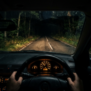 Vista hiperrealista del conductor en la noche con faros tenues que apenas iluminan el camino asfaltado